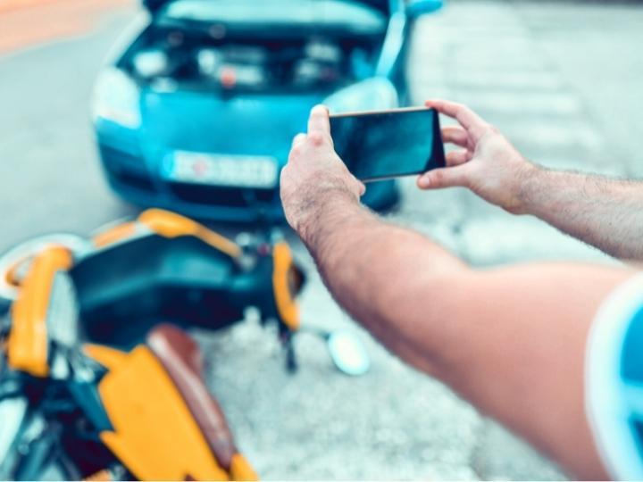 man-takes-a-photo-of-the-damage-after-a-motorcycle-accident